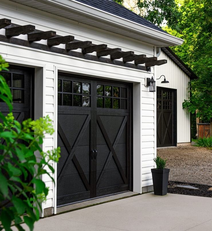 Black carriage house garage doors on a white clapboard garage