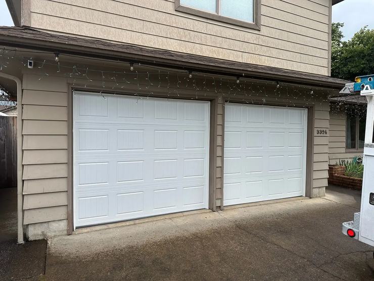 Two white sectional garage doors on a beige home